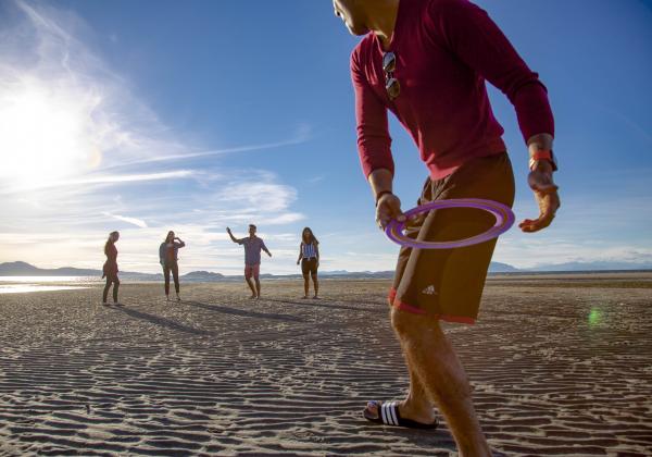 Students play frisbee at a beach